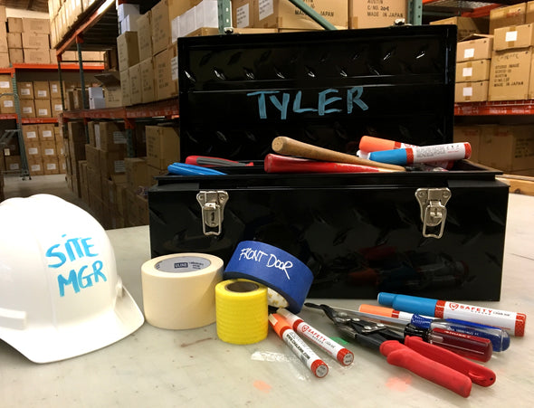 Image of warehouse table with toolbox, hard hat and tape roll with identifying markings using Chalk Ink fluorescent safety markers