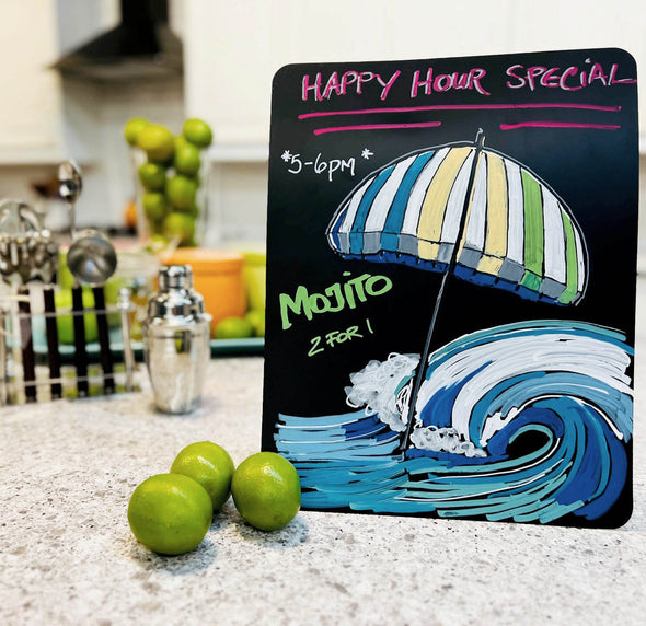 Image of Happy hour menu written on chalkboard paper on countertop using chalk ink liquid chalk markers with colorful striped beach umbrella