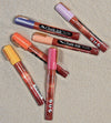 Product image of chalk ink liquid chalk markers in sunset inspired colors laying on beach sand