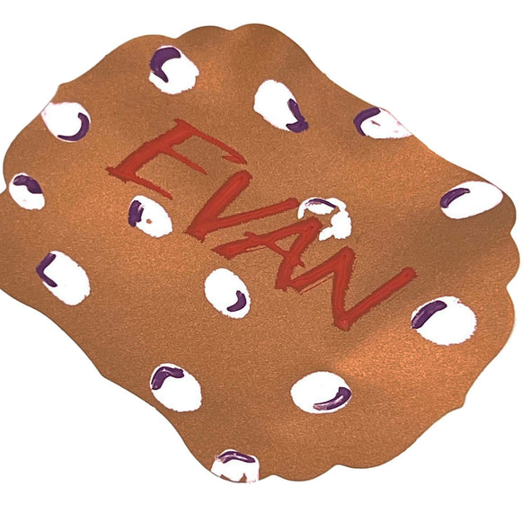 Closeup image of copper metallic adhesive label with the word Evan written on it using chalk ink liquid chalk markers