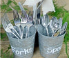 Image of metal buckets holding spoons and forks with the words forks and spoons written on the side using chalk ink white liquid chalk markers